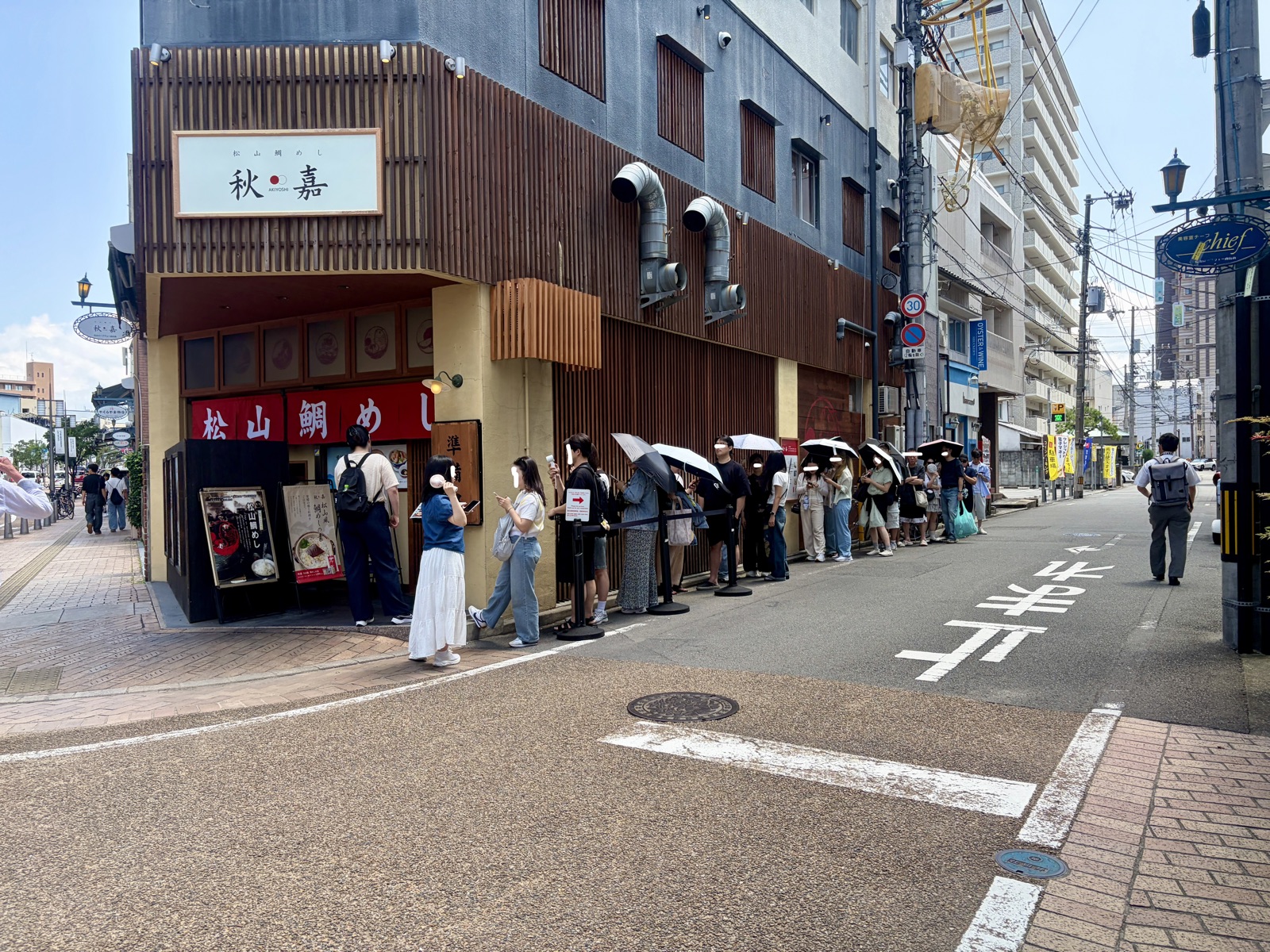 秋嘉の開店前にできた行列。炎天下で日傘をさして並ぶ人々