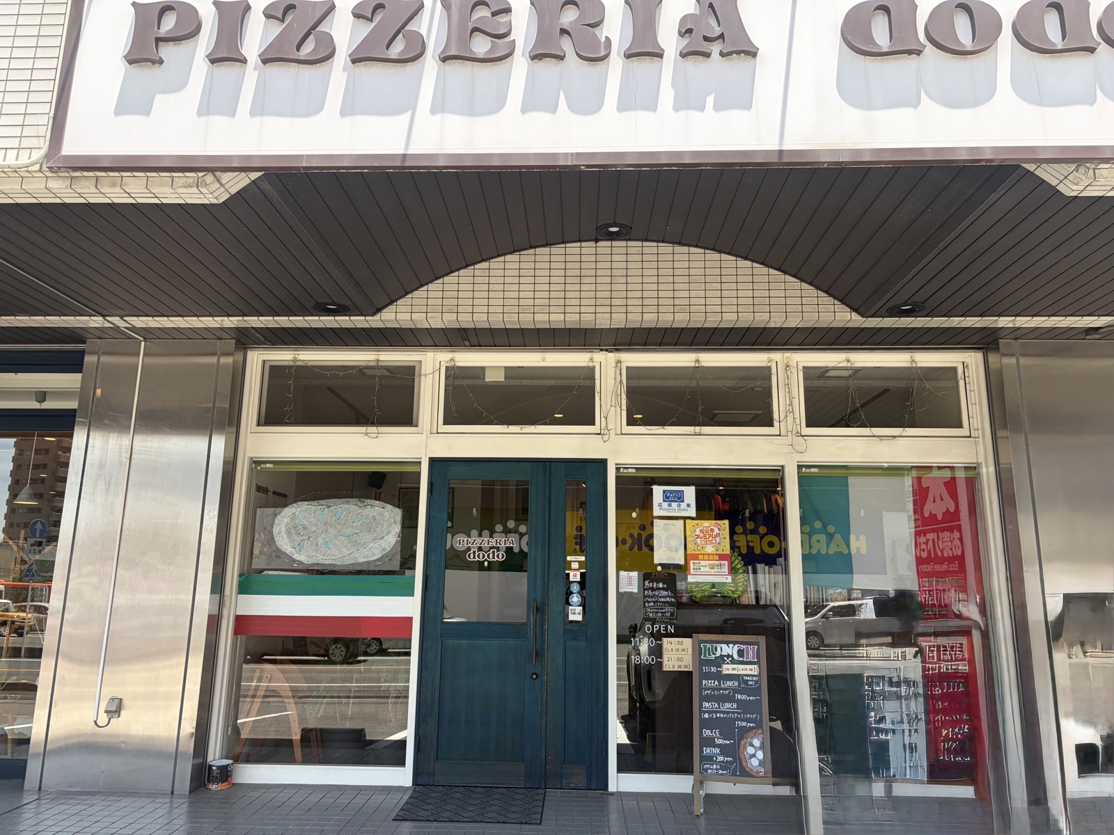 松山・南久米町のPIZZERIA dodoの外観。青い扉とイタリアンカラーの装飾が目印
