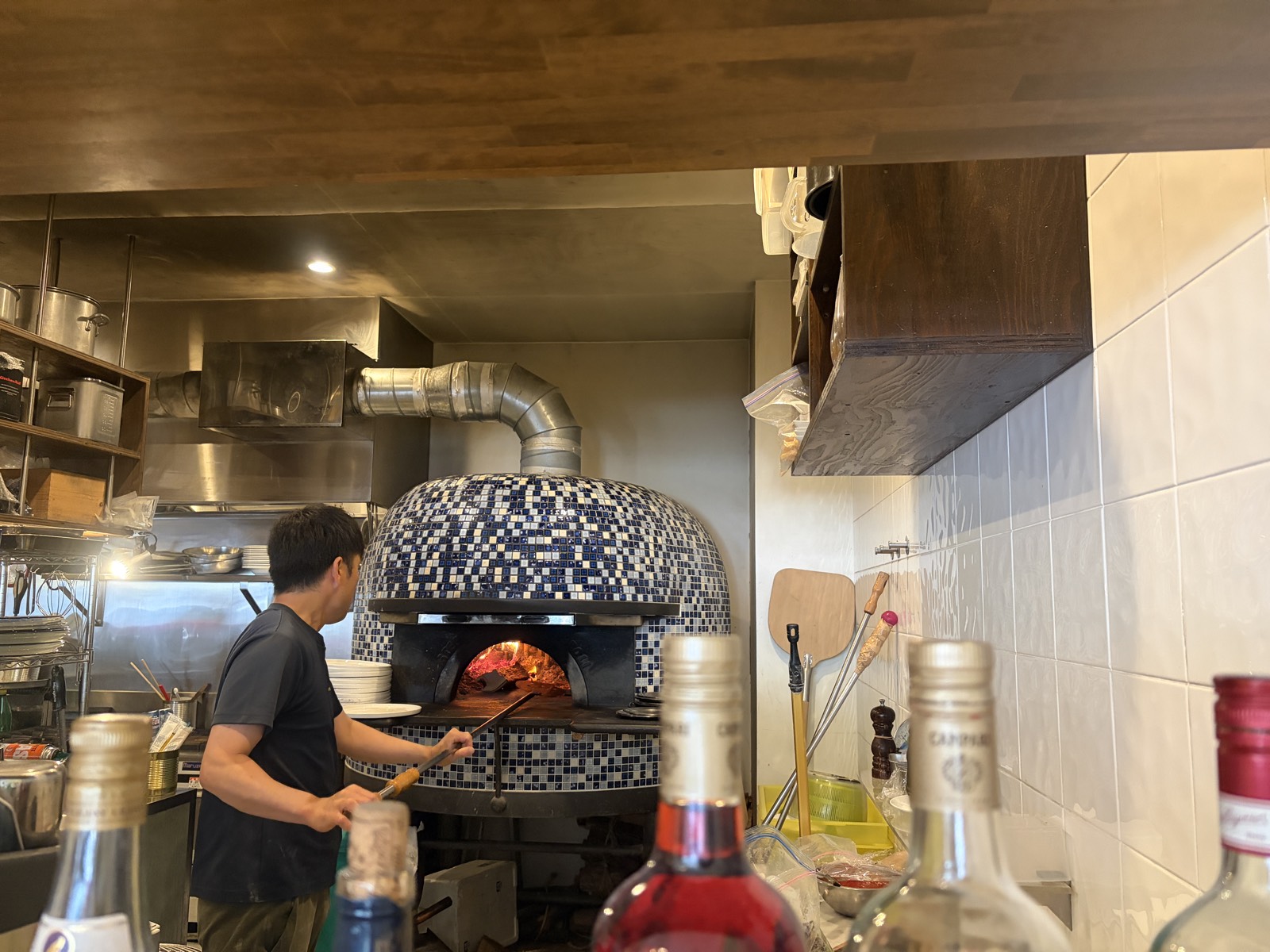 PIZZERIA dodoの厨房にある青いモザイクタイルの薪窯。中で薪の炎が燃えている