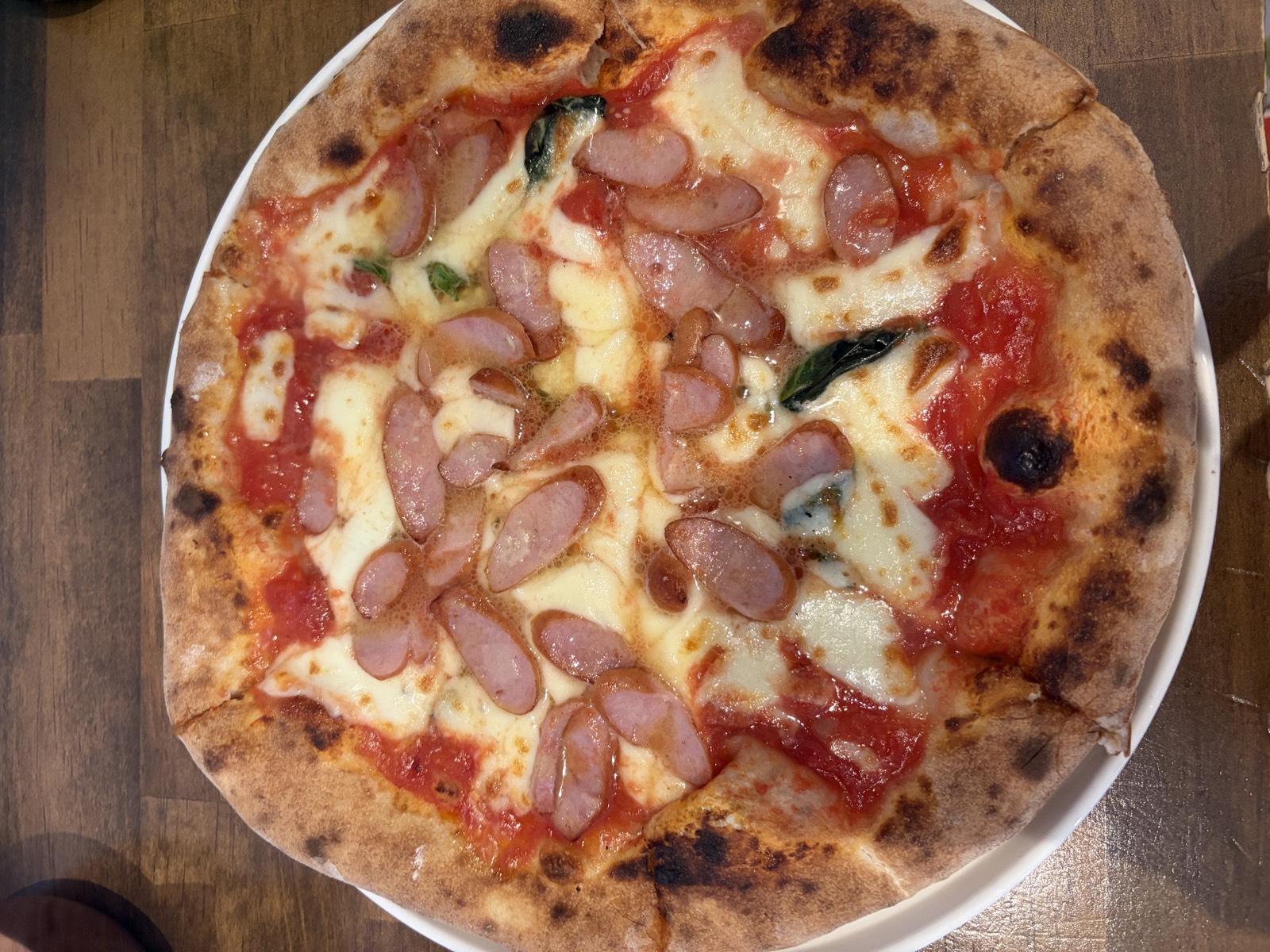 PIZZERIA dodoのマルゲリータウリュステル。トマトソースとモッツァレラに輪切りのソーセージをのせた薪窯ピザ