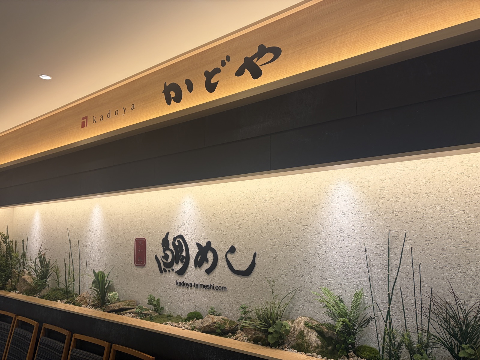 かどやの店内壁にある鯛めしのロゴとサイトアドレスの装飾