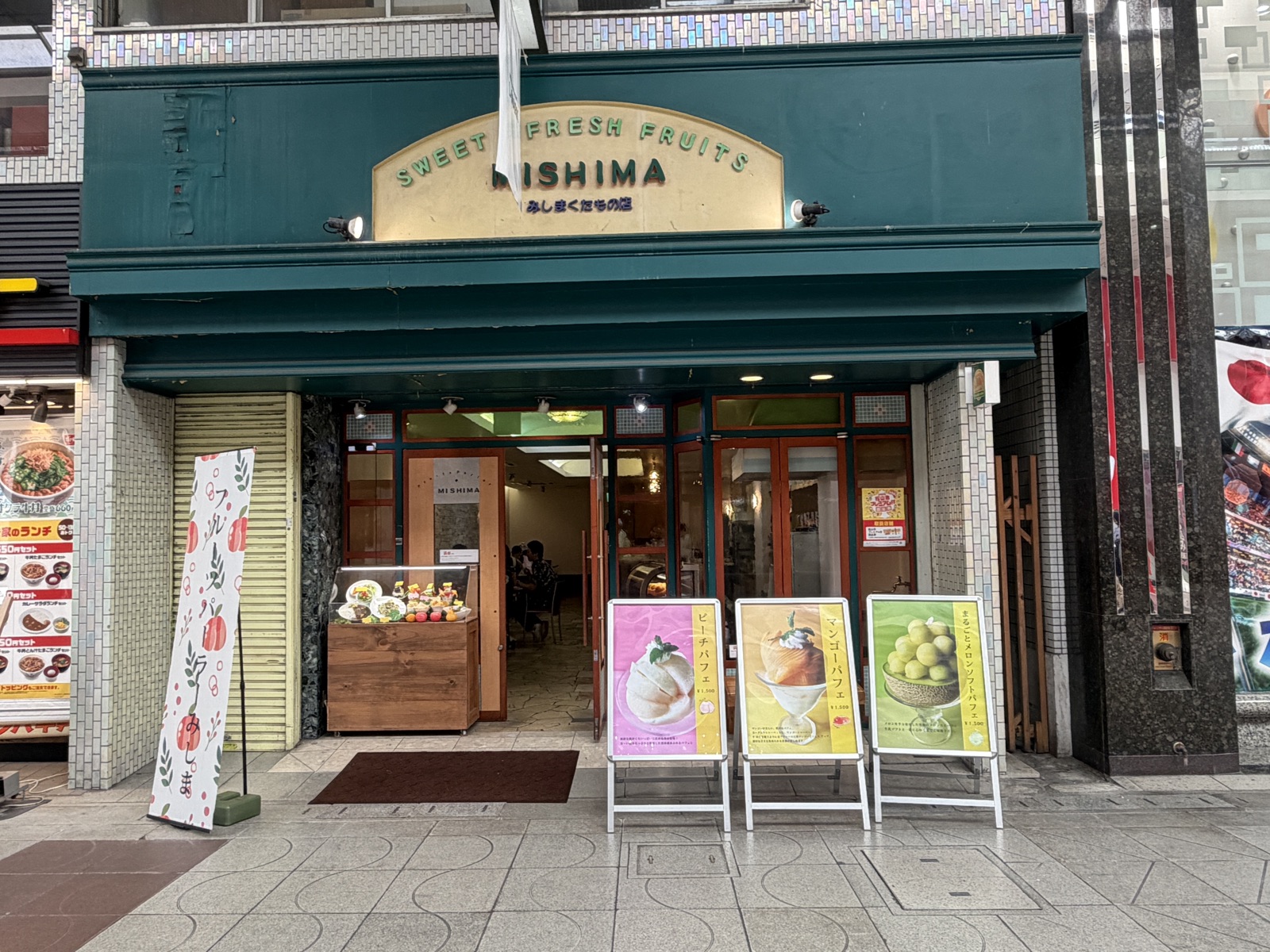大街道商店街にあるフルーツパーラーみしまの外観。緑の庇と「MISHIMA」の看板、店頭のパフェ案内