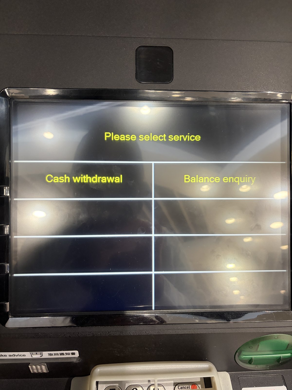 ATMの画面。「Please select service」の下に「Cash withdrawal」と「Balance enquiry」