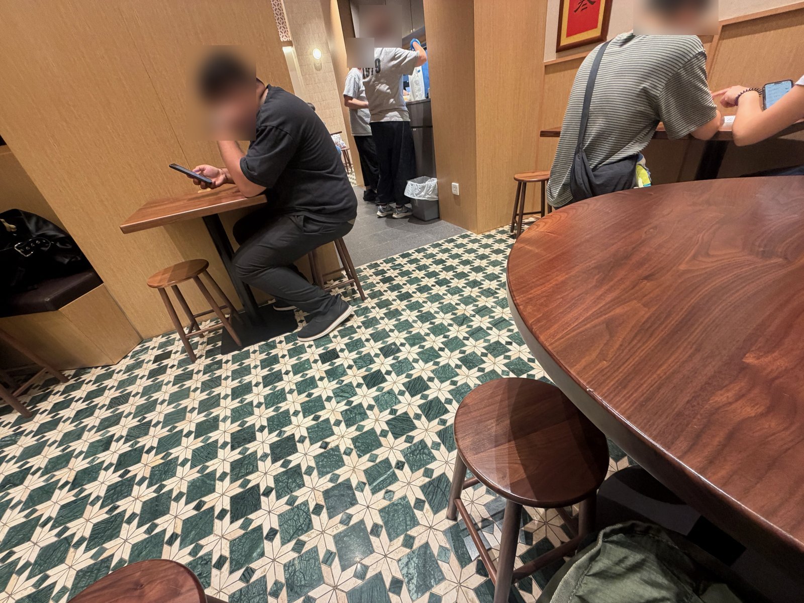 店内。木のテーブルと丸いいす、緑と白の模様の床
