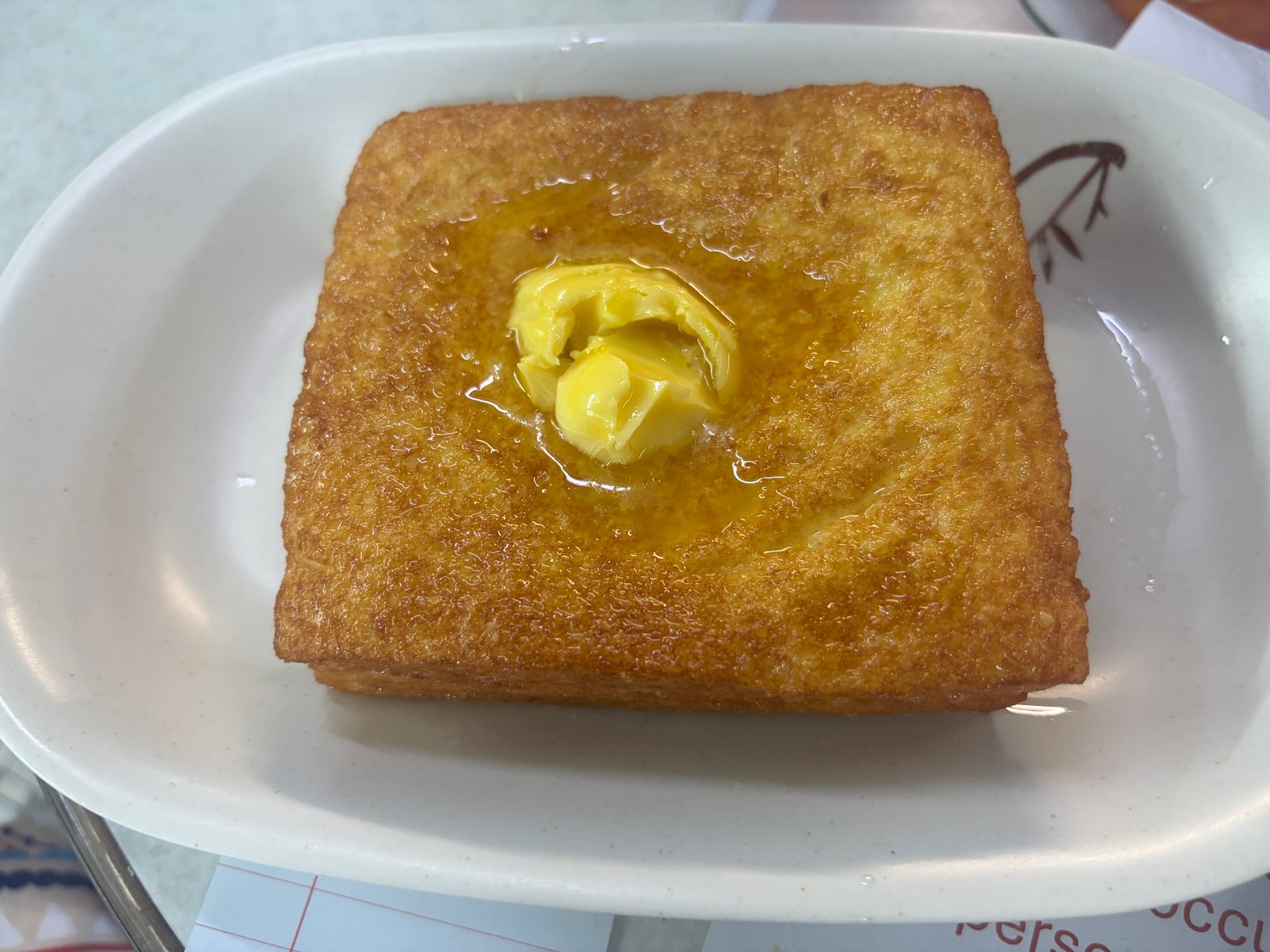 四角いフレンチトースト。表面はこんがり揚がっていて、真ん中にバターがのっている