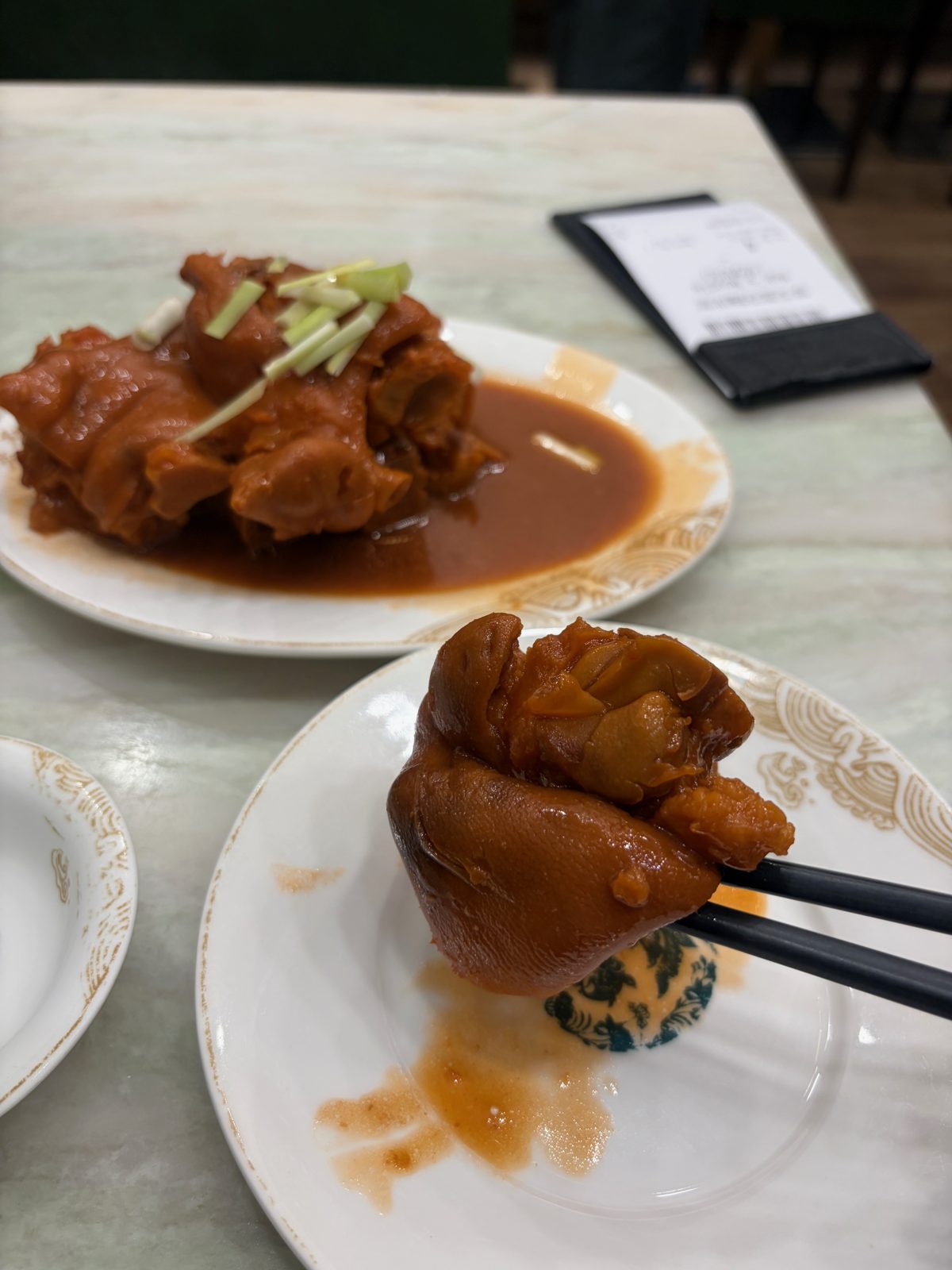 豚足の煮込み。赤茶色のたれに、ニラがのっている