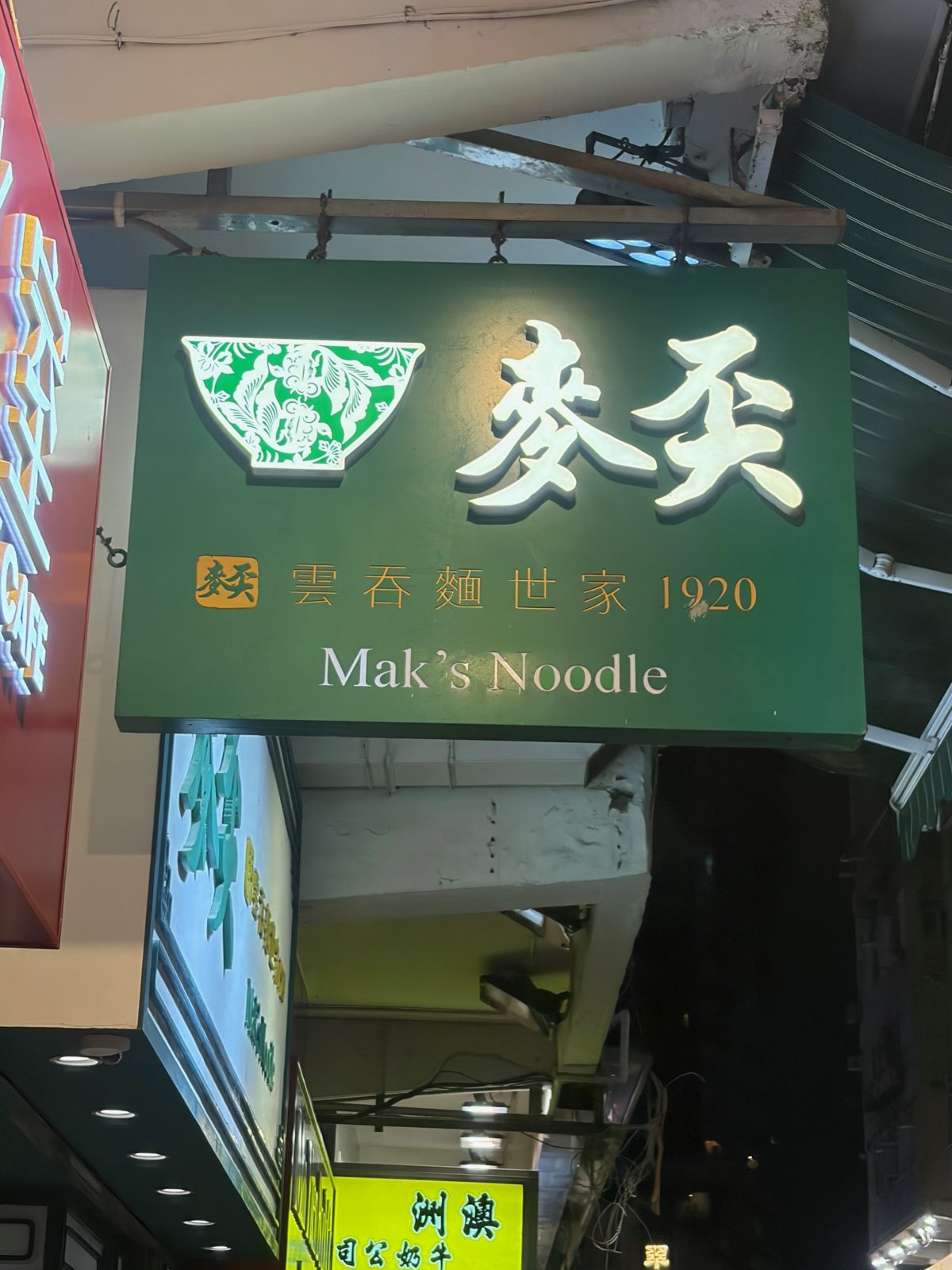 緑の看板に「麥奀」「雲吞麵世家 1920」「Mak's Noodle」の文字