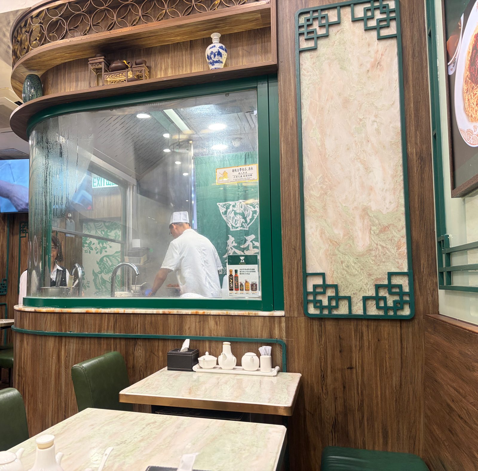 ガラス越しに見える厨房。白い服の料理人が麺をゆでている