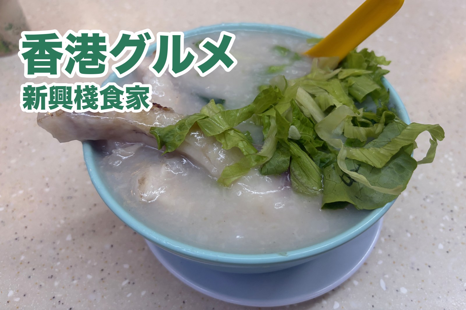 新興棧食家の魚腩粥。お椀から焼き色のついた魚がはみ出し、レタスがのっている