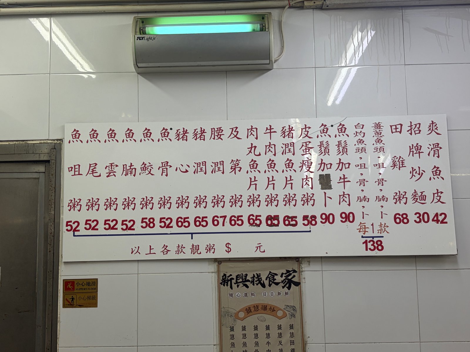 壁に貼られた、漢字だけのメニュー。粥の名前と値段が縦書きで並んでいる